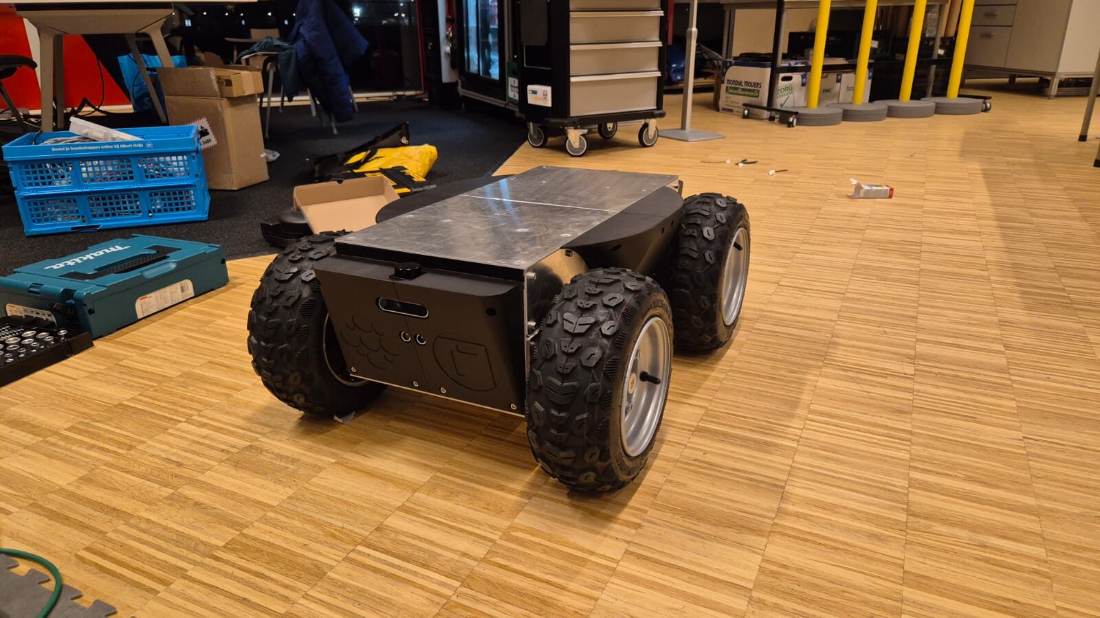 Assembled SLIP chassis on the workshop floor during initial build, showing the aluminum deck and skid-steer wheels.