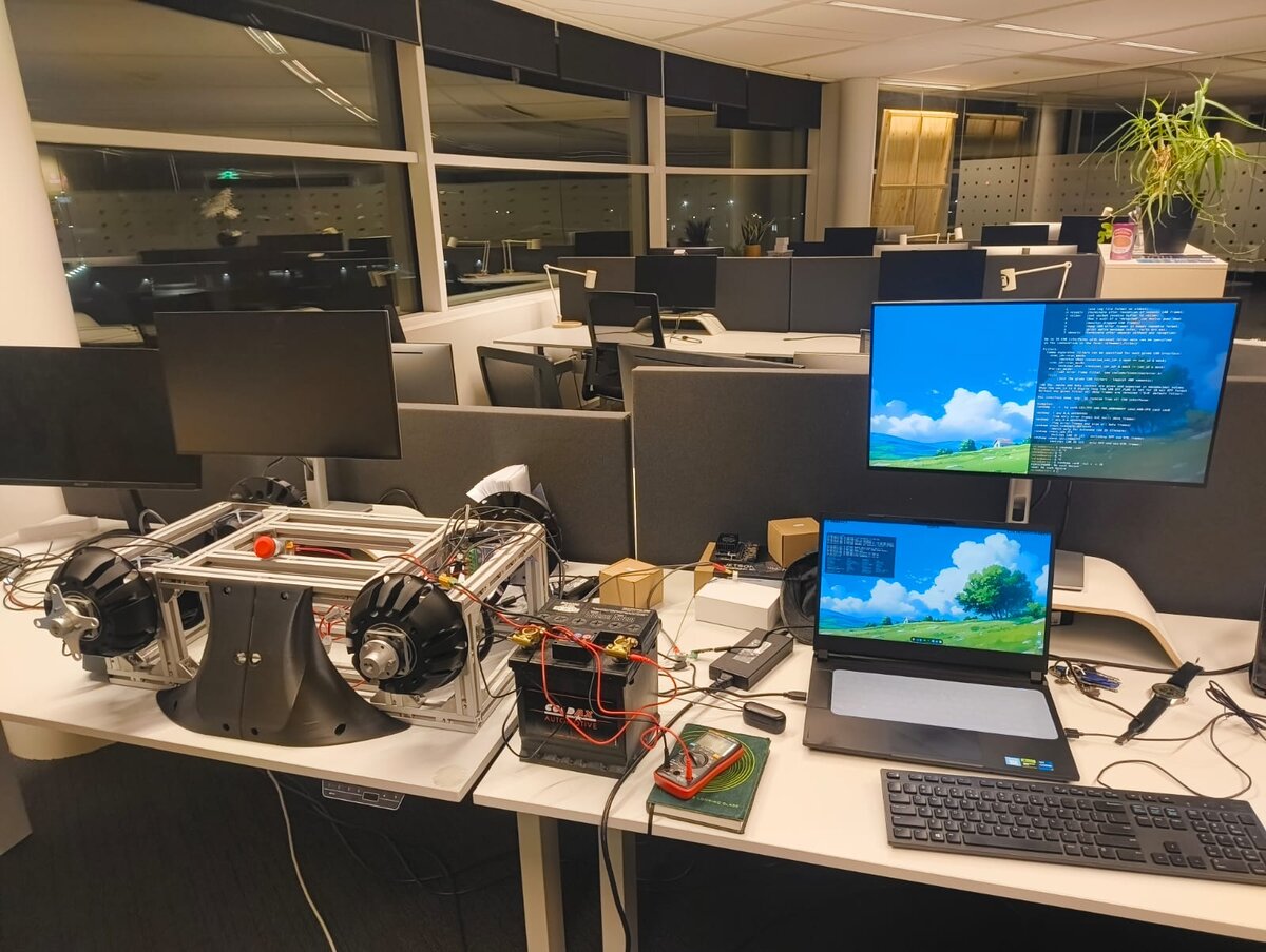Bare SLIP chassis on hub motors, powered from a lead-acid car battery on a desk, with a terminal showing a CAN interface error in the background.