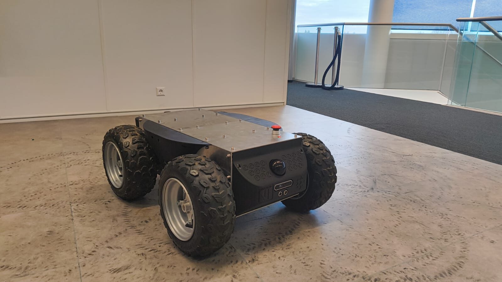 SLIP, a four-wheel skid-steer ground robot with all-terrain tires and an aluminum chassis, photographed indoors at RoboHouse.